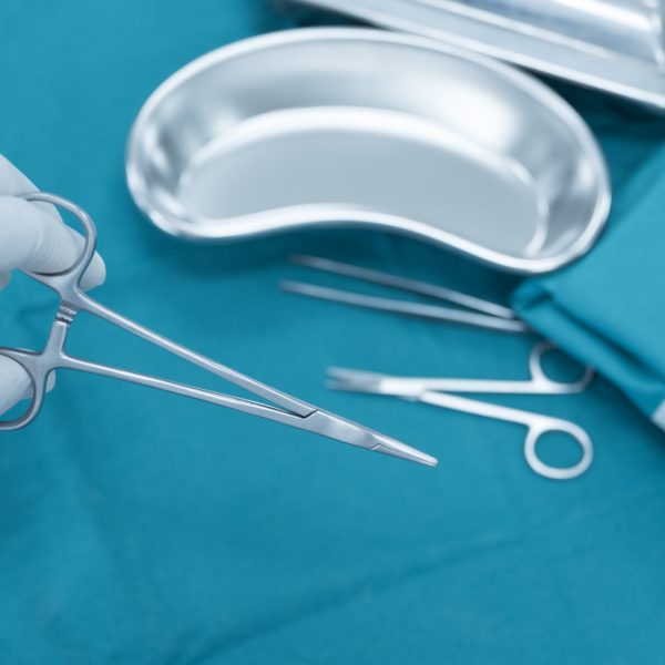 Surgeon doctor’s hand with hygiene glove taking scissor surgical set and medical equipment on green surgical tray inside operating room.Sterile surgical instrument tool equipment for surgery. Surgeon doctor's hand with hygiene glove taking scissor surgical set and medical equipment on green surgical tray inside operating room.Sterile surgical instrument tool equipment for surgery.Infection control